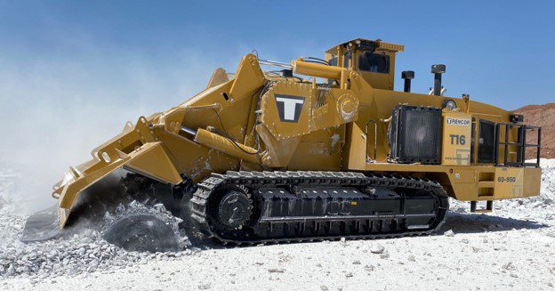 Track-mounted surface mining machine cutting rock at an open-pit site